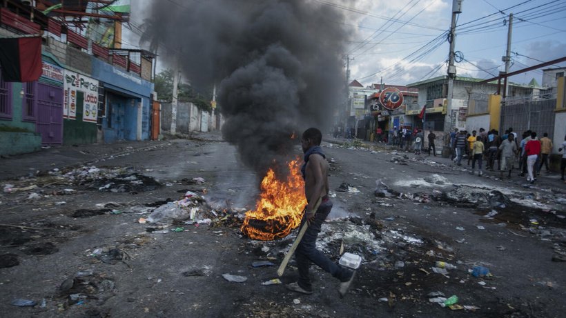 Un homme passe devant des pneus en feu lors d'une manifestation demandant la démission du Premier ministre Ariel Henry, à Port-au-Prince, en Haïti, le 10 octobre 2022. © Odelyn Joseph, AP