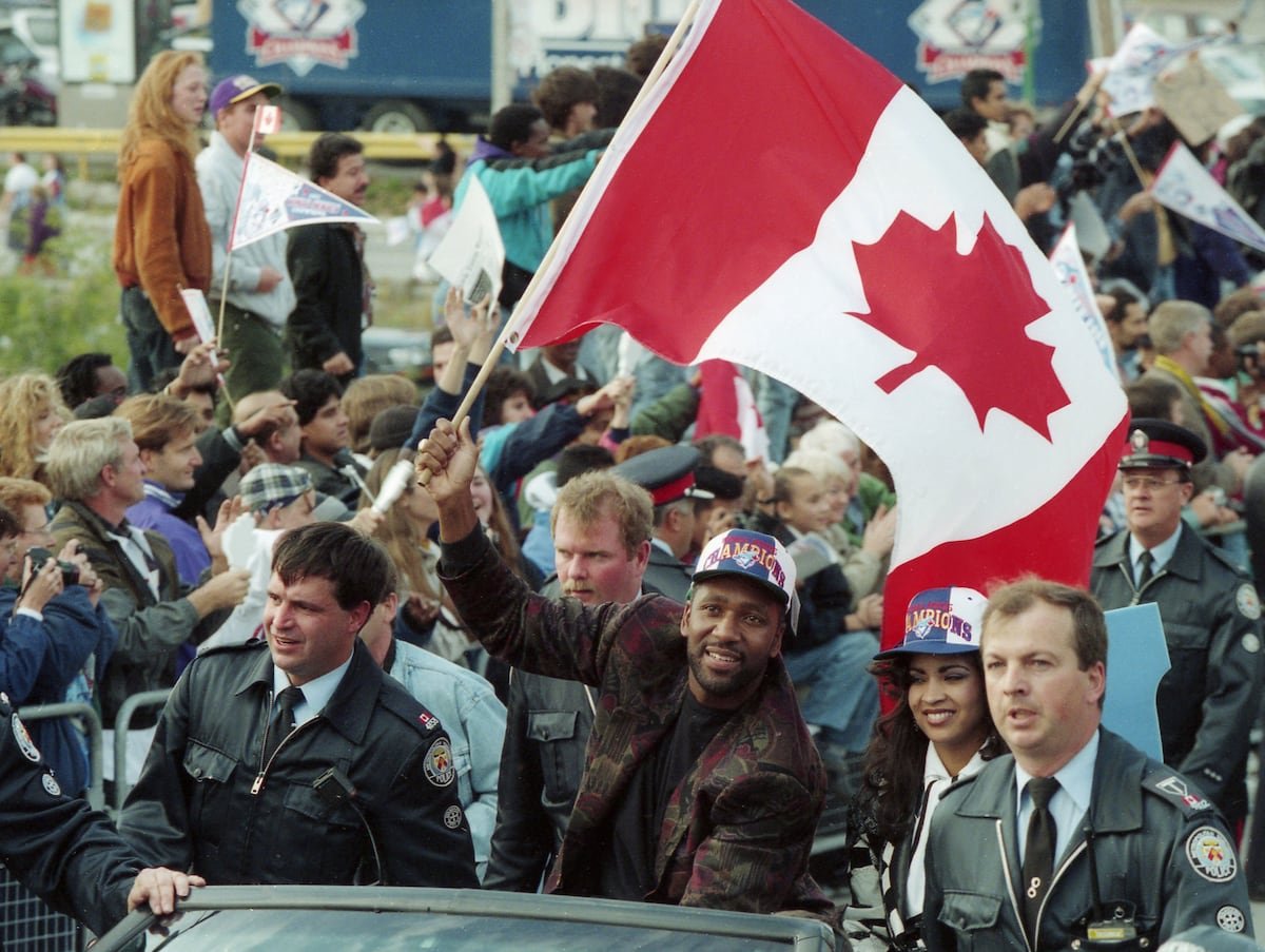 Joe Carter, joueur des Blue Jays de Toronto, agite le drapeau canadien aux côtés de sa femme Diana lors du défilé des vainqueurs des Séries mondiales à Toronto, le dimanche 24 octobre 1993.